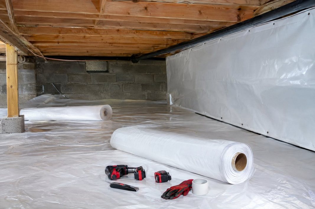 Technician inspecting and sealing a crawl space with a vapor barrier