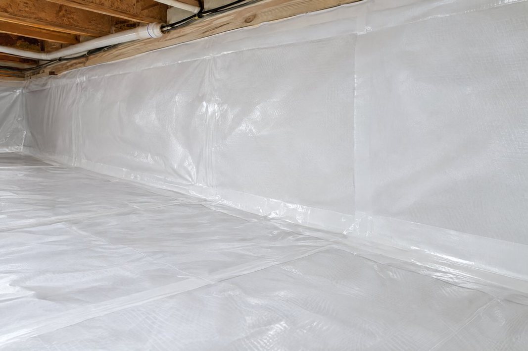 Crawl space sealed with a white reinforced vapor barrier on the floor and foundation walls